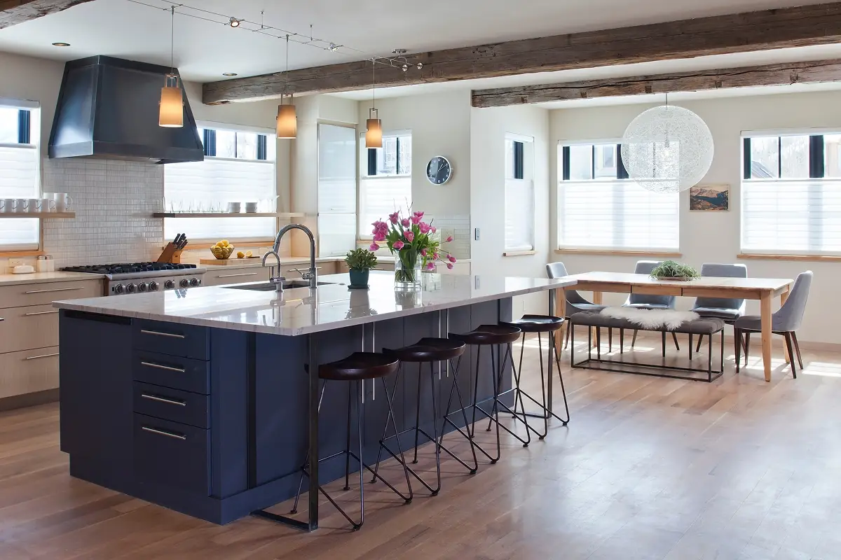 Spacious kitchen with navy island, wood accents, and open dining area beneath reclaimed ceiling beams.
