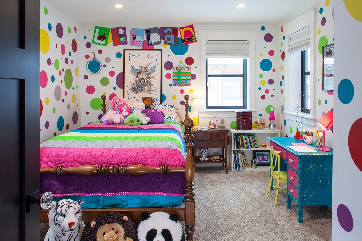 Bright kids room in Crested Butte with polka-dot walls, colorful bedding, plush toys, and a teal desk with hand-painted drawers.