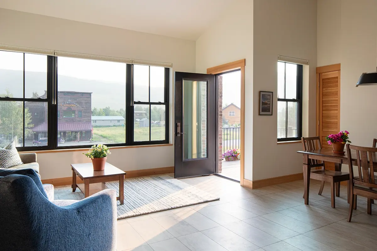 Bright open-plan interior with mountain views through expansive windows and access to private outdoor balcony.