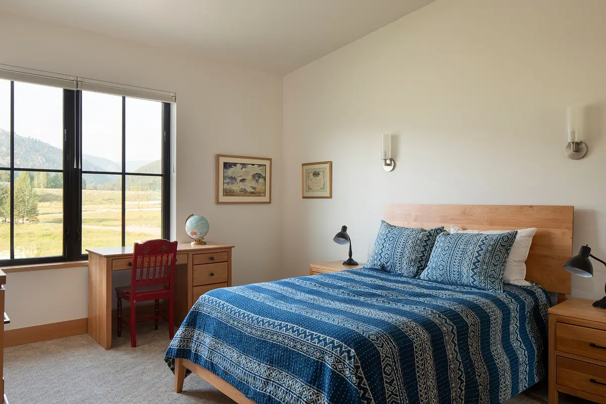 Bedroom interior with large picture window overlooking Crested Butte’s mountain landscape and open meadow.