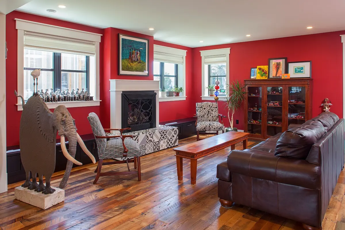 Colorful mountain living room in Crested Butte featuring red walls, curated art, reclaimed wood floors, and eclectic furnishings.