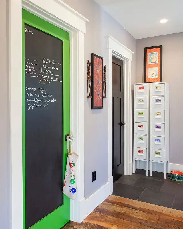 Functional mudroom entry in Crested Butte with chalkboard door, labeled cubbies, and hardwood floors with slate tile transition.