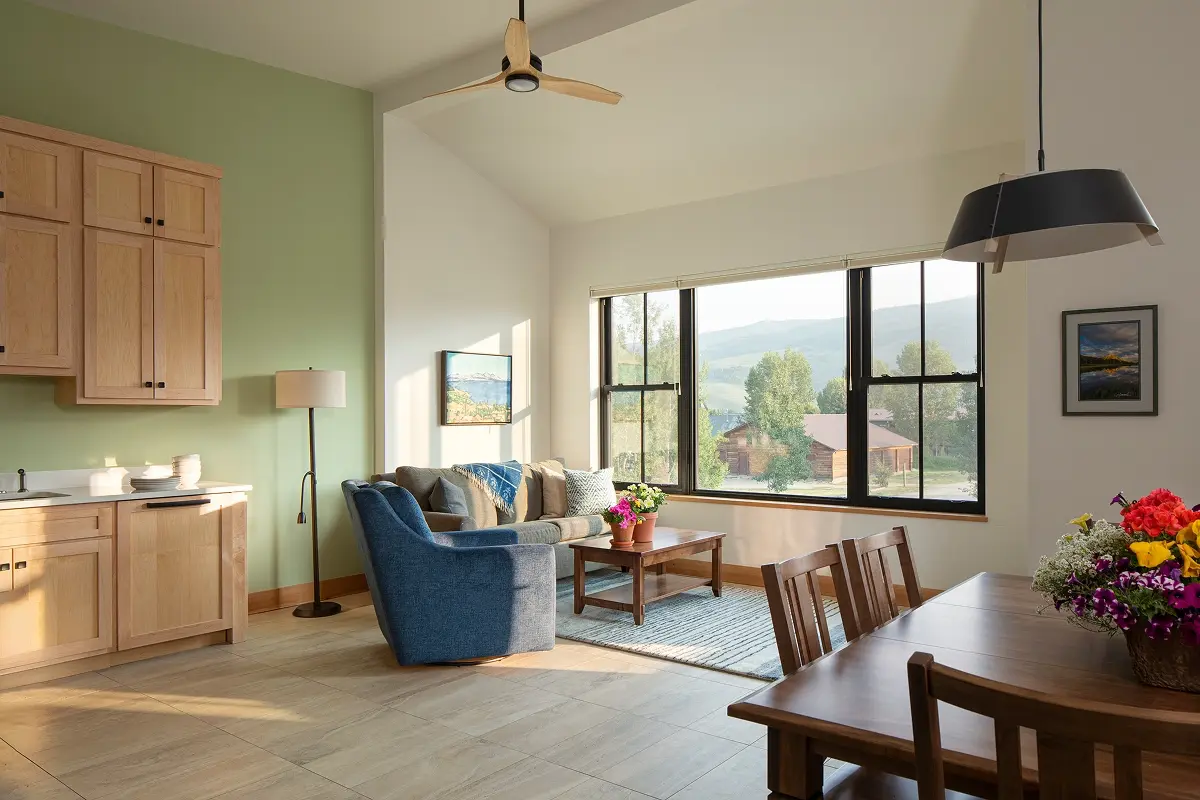 Cozy living room interior with green accent wall, large windows, and natural light in Crested Butte South apartment.