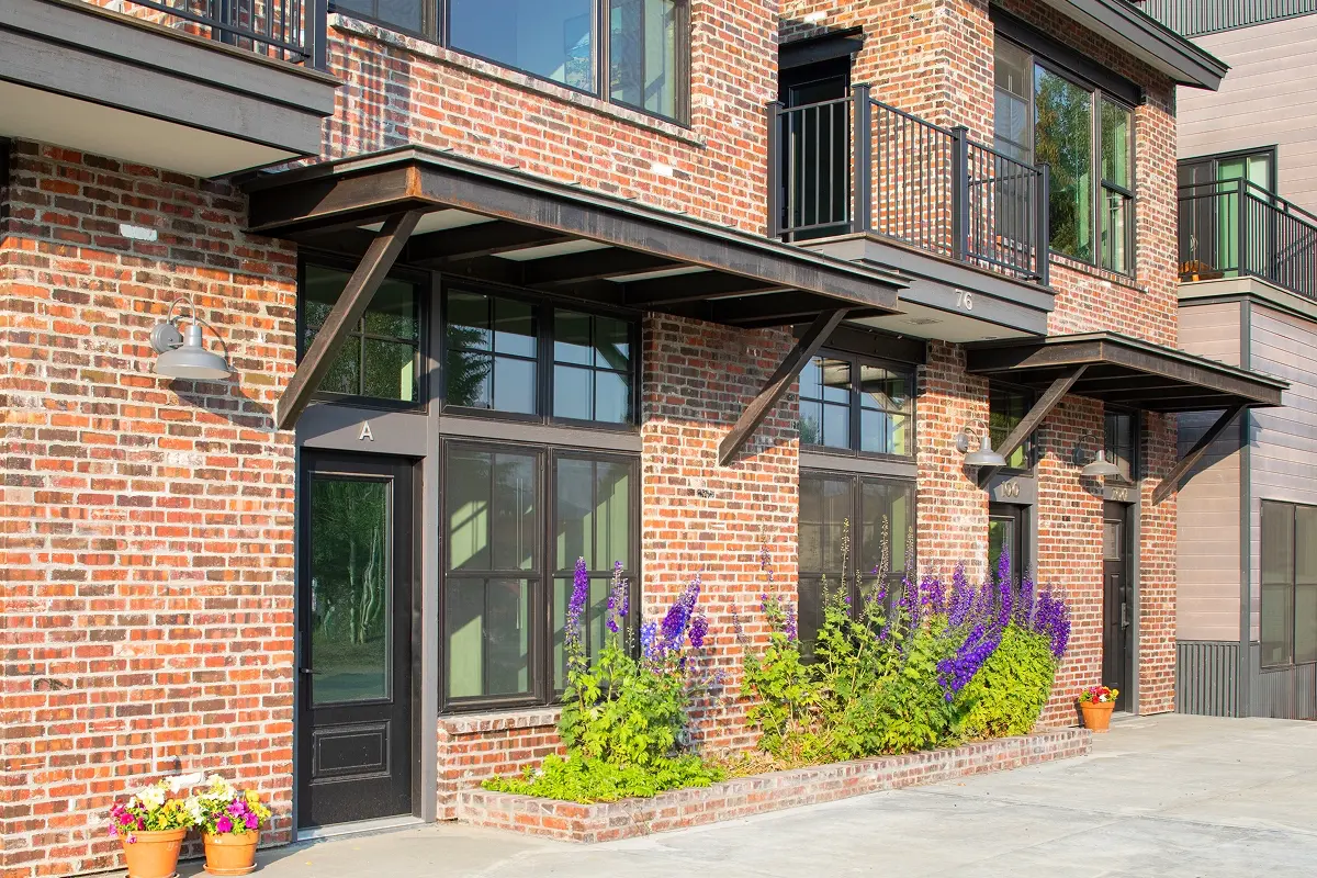 Brick exterior with steel canopy and vibrant landscaping in front of mixed-use building in Crested Butte South.