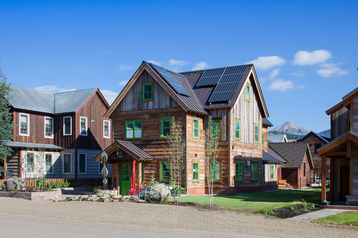Side-angle view of a custom Crested Butte home featuring solar panels, reclaimed wood siding, and vibrant green window trim.