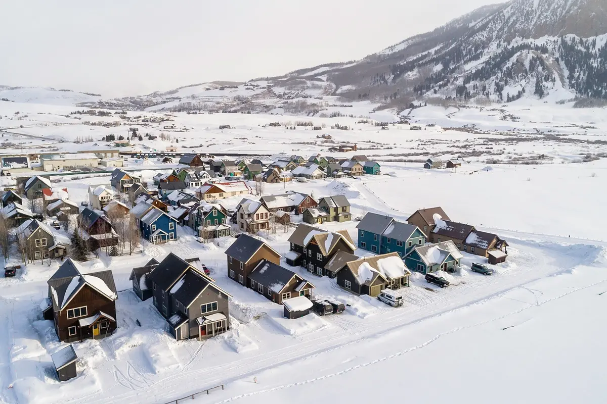 A row of vibrant, affordable housing units in Crested Butte surrounded by deep snow and backdropped by Mt. Crested Butte.