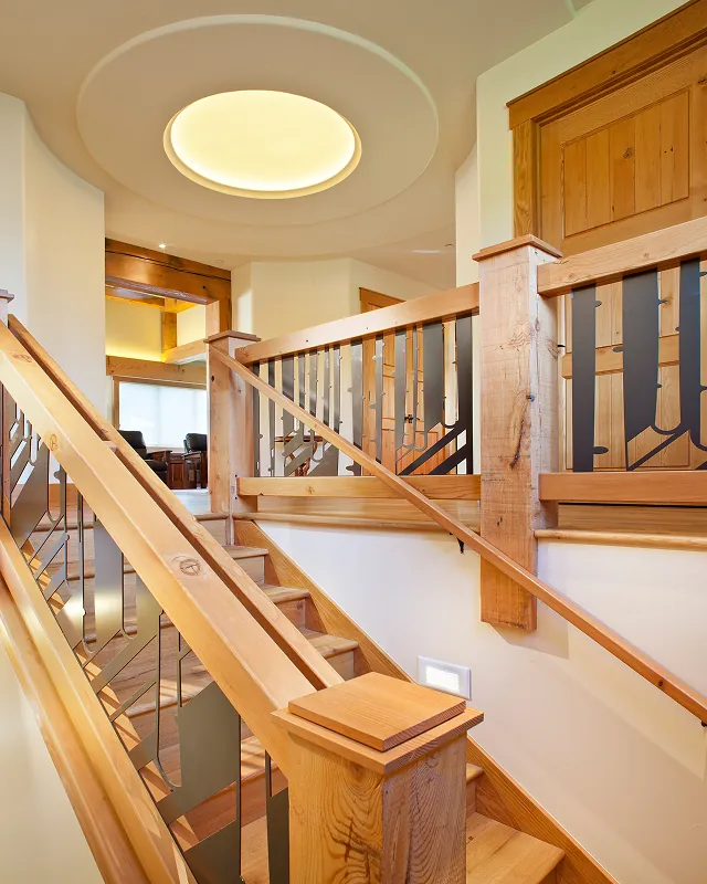 Custom timber staircase with steel accent railings and illuminated ceiling detail in Colorado mountain home.
